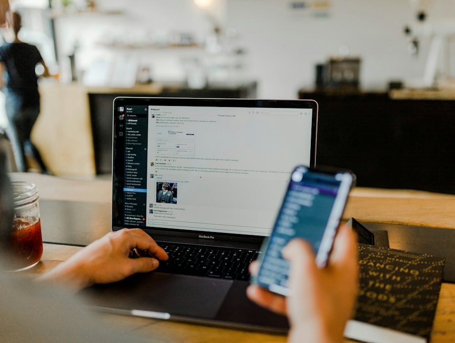 Person checking messages on a phone beside a laptop